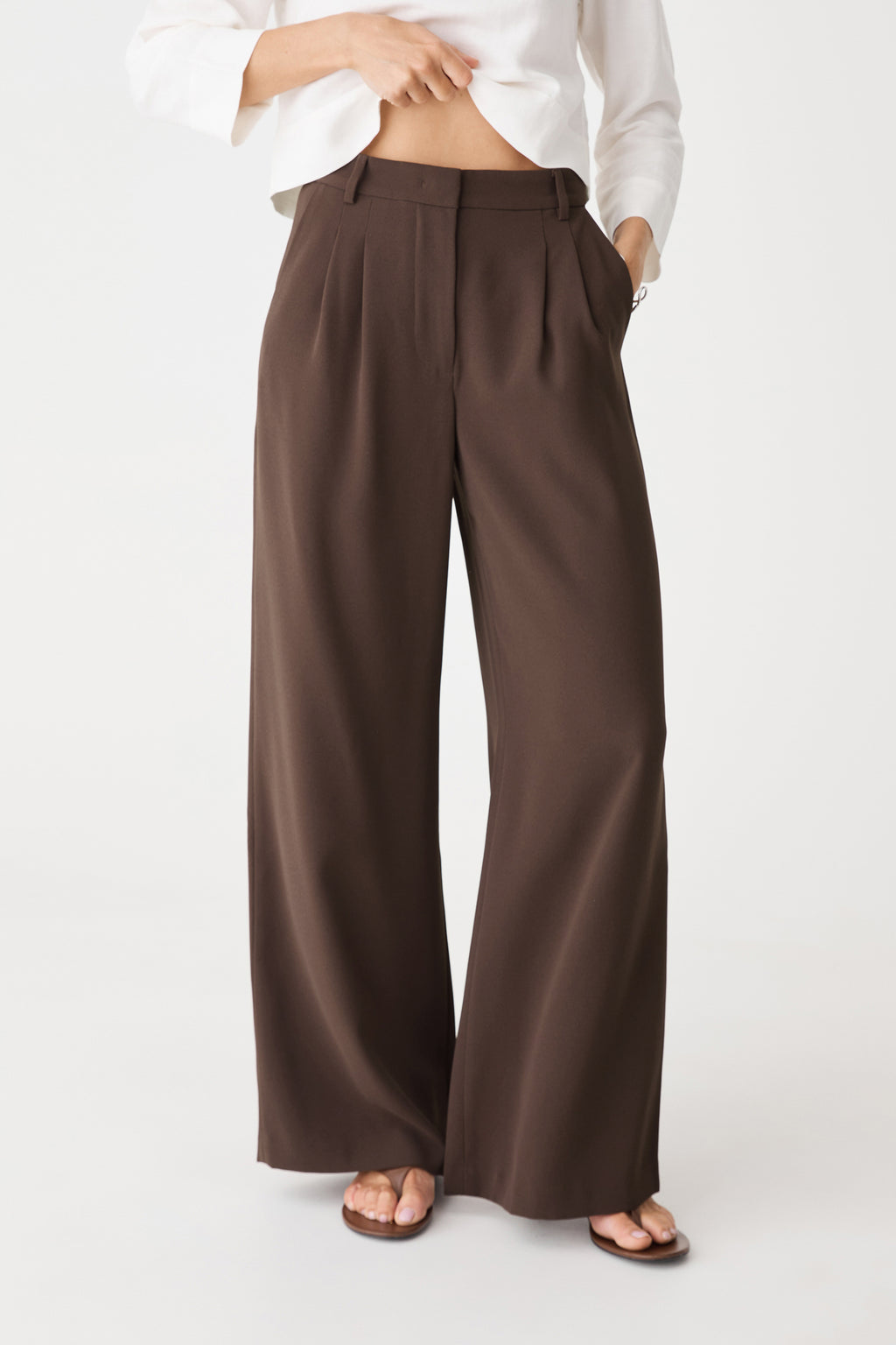 Close-up front view of the chocolate pants showing high waistband, front pleats and slant pockets