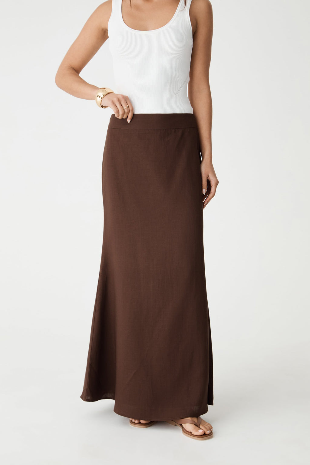 Close-up front view of the chocolate maxi skirt showing high-waisted waistband and flute hem