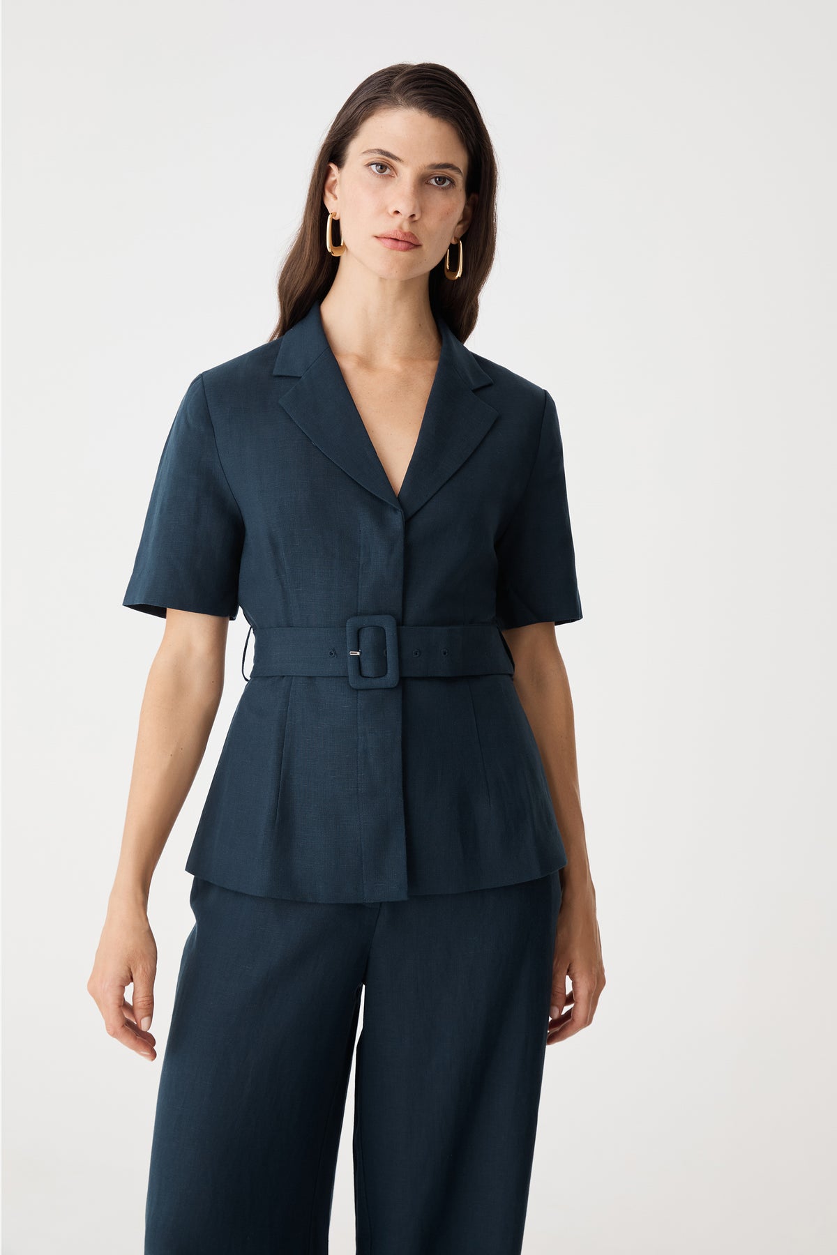 Close-up front view of the navy blazer showing notch lapels, short sleeves and covered buckle belt