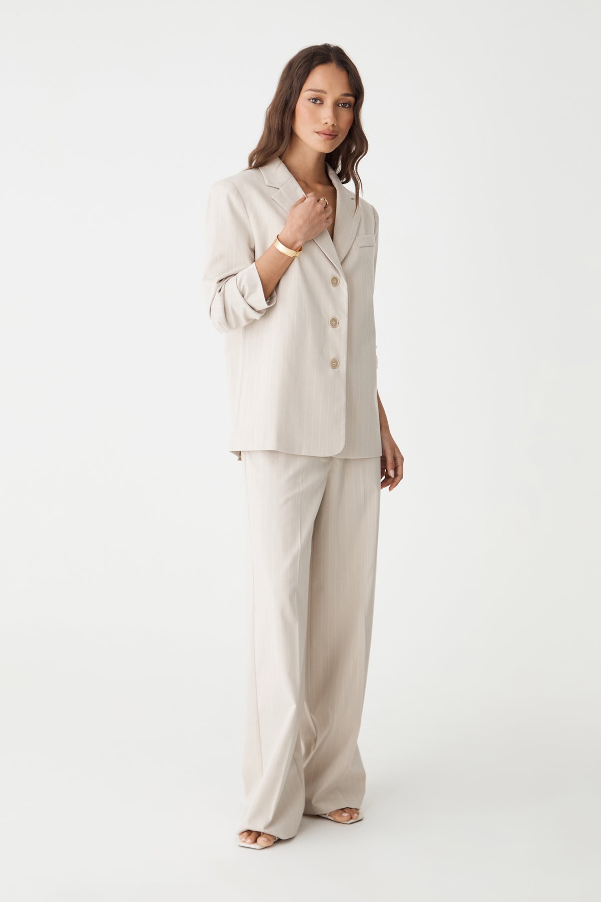 Side view of the beige pinstripe blazer worn open over matching trousers