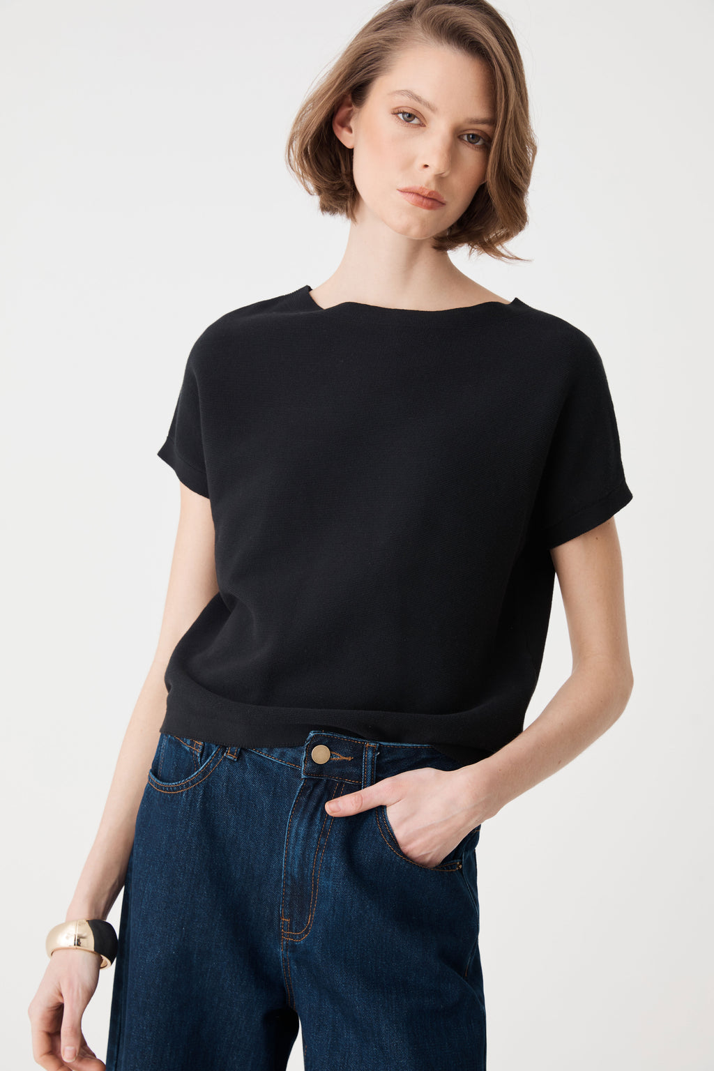 Close-up front view of the black knit top showing boat neckline and short cuffed sleeves