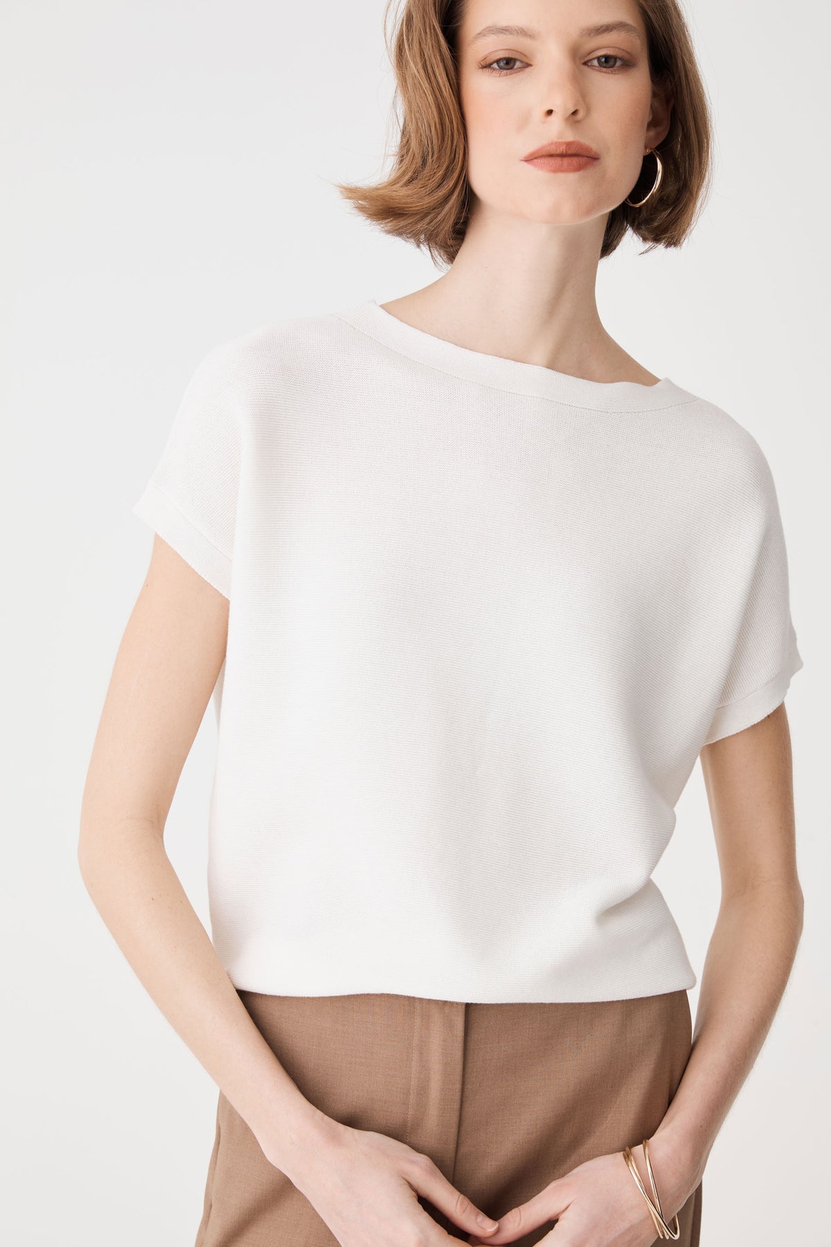 Front detail of the ivory knit top showing folded sleeve cuffs and horizontal ribbed texture