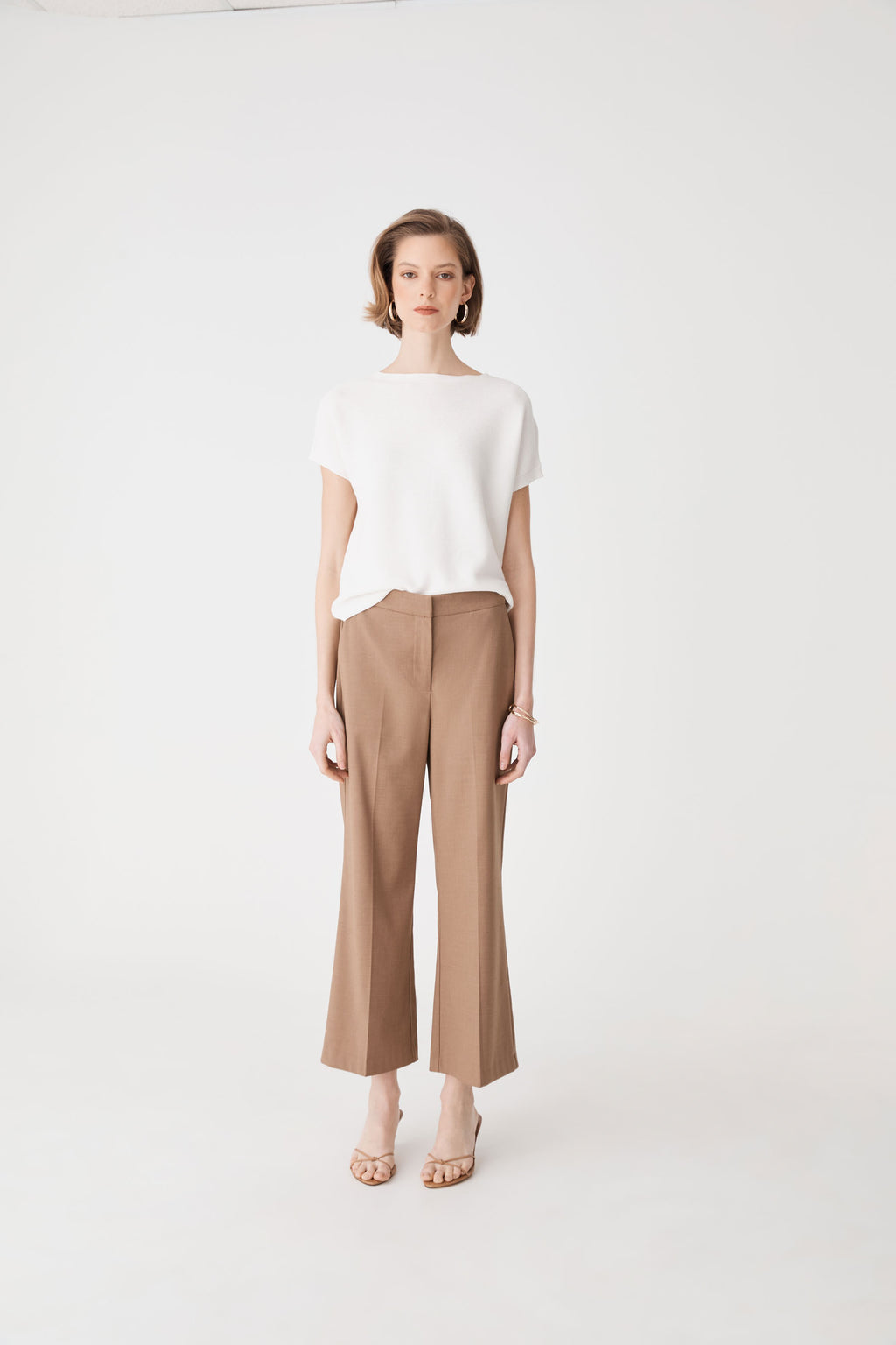 Full-length front view of the ivory knit top worn with tan wide-leg trousers