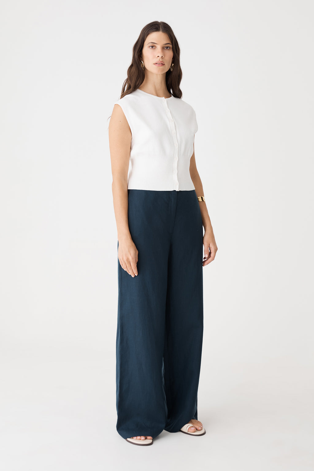 Side view of the ivory Faye Sleeveless Button Up Knit with navy wide-leg trousers