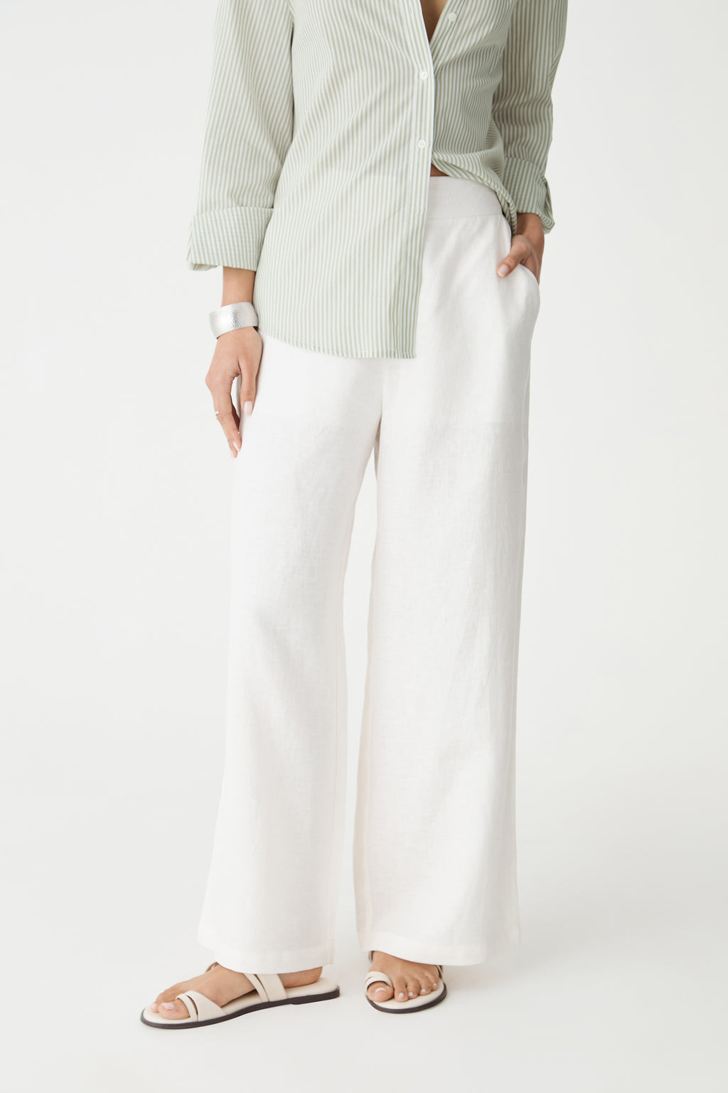 Close-up of the ivory wide-leg pants, front view from waist to hem with flat sandals