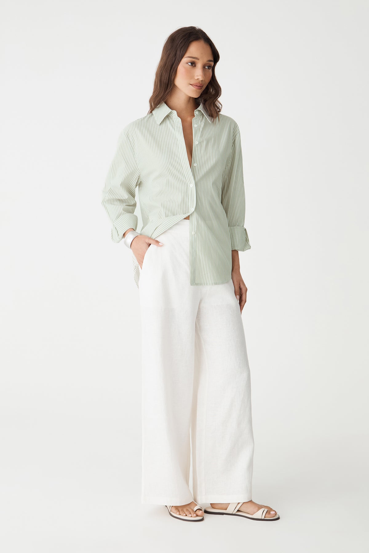 Side-front view of the ivory linen wide-leg pants worn with a green shirt
