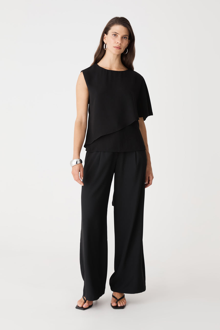 Cecilia Asymmetric Top in black, front view with layered angular hem, worn with black wide-leg trousers