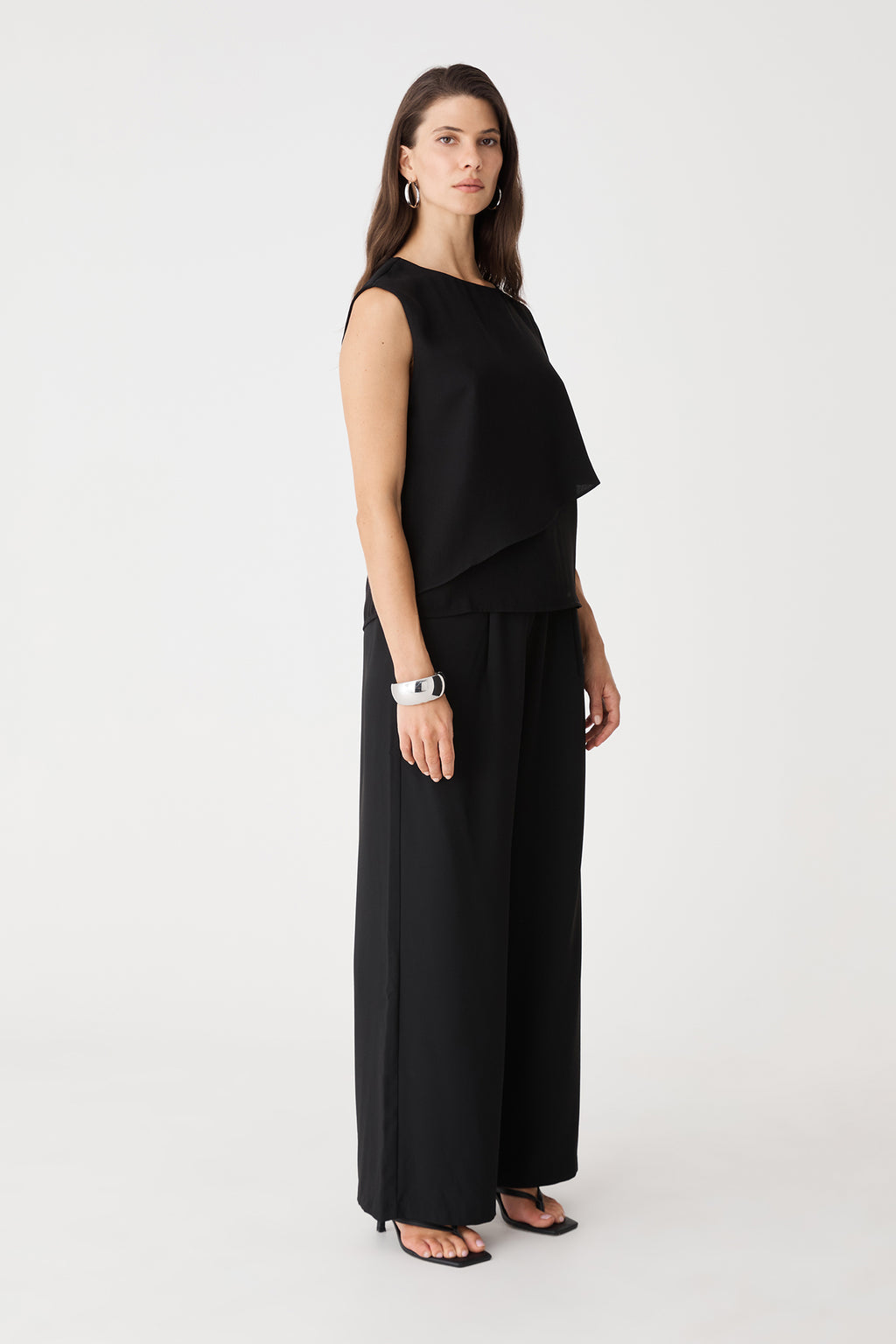 Side view of the black asymmetric top with full-length trousers
