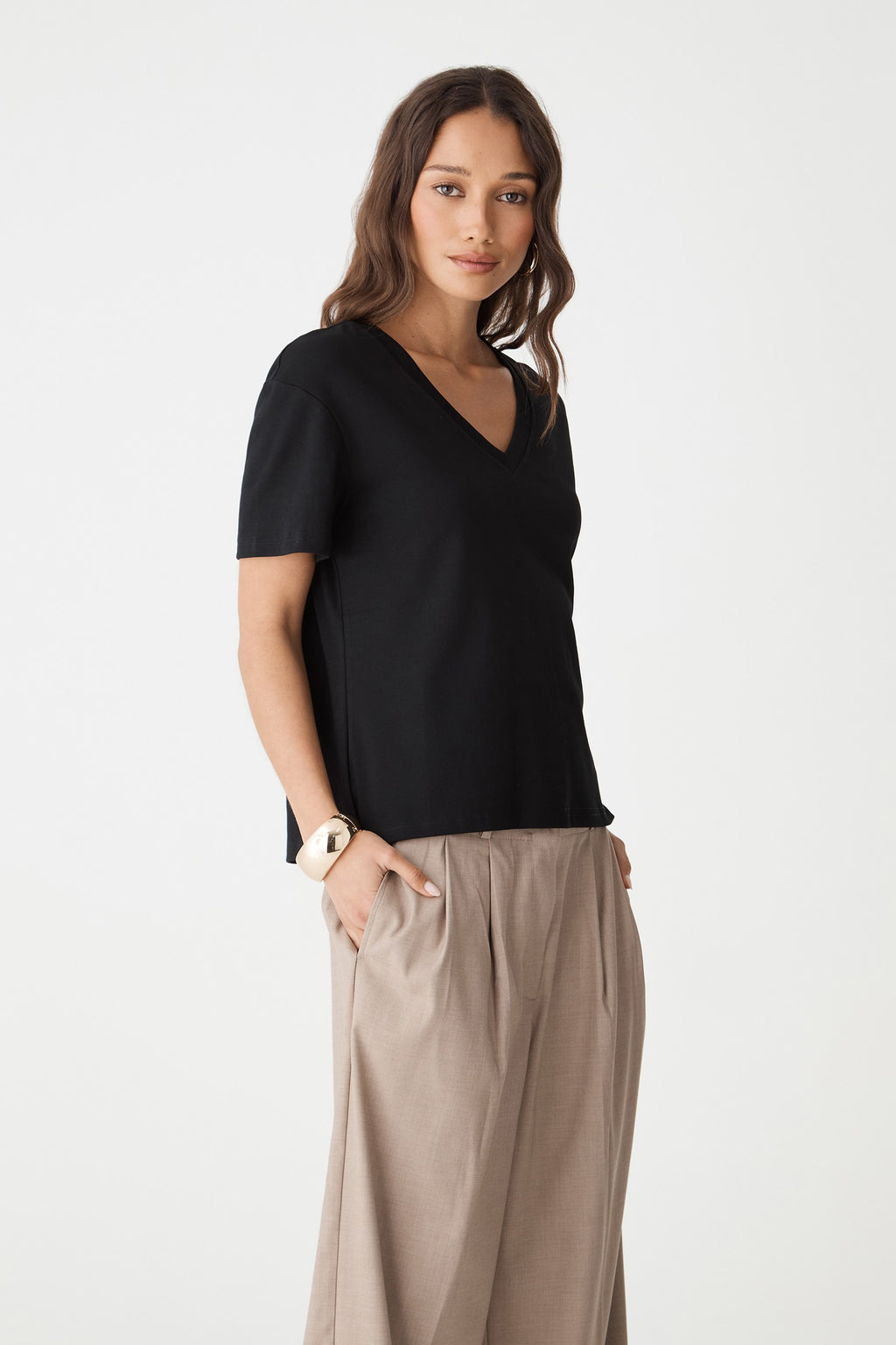 Side front view of the black May V-Neck Cotton T-Shirt with taupe trousers