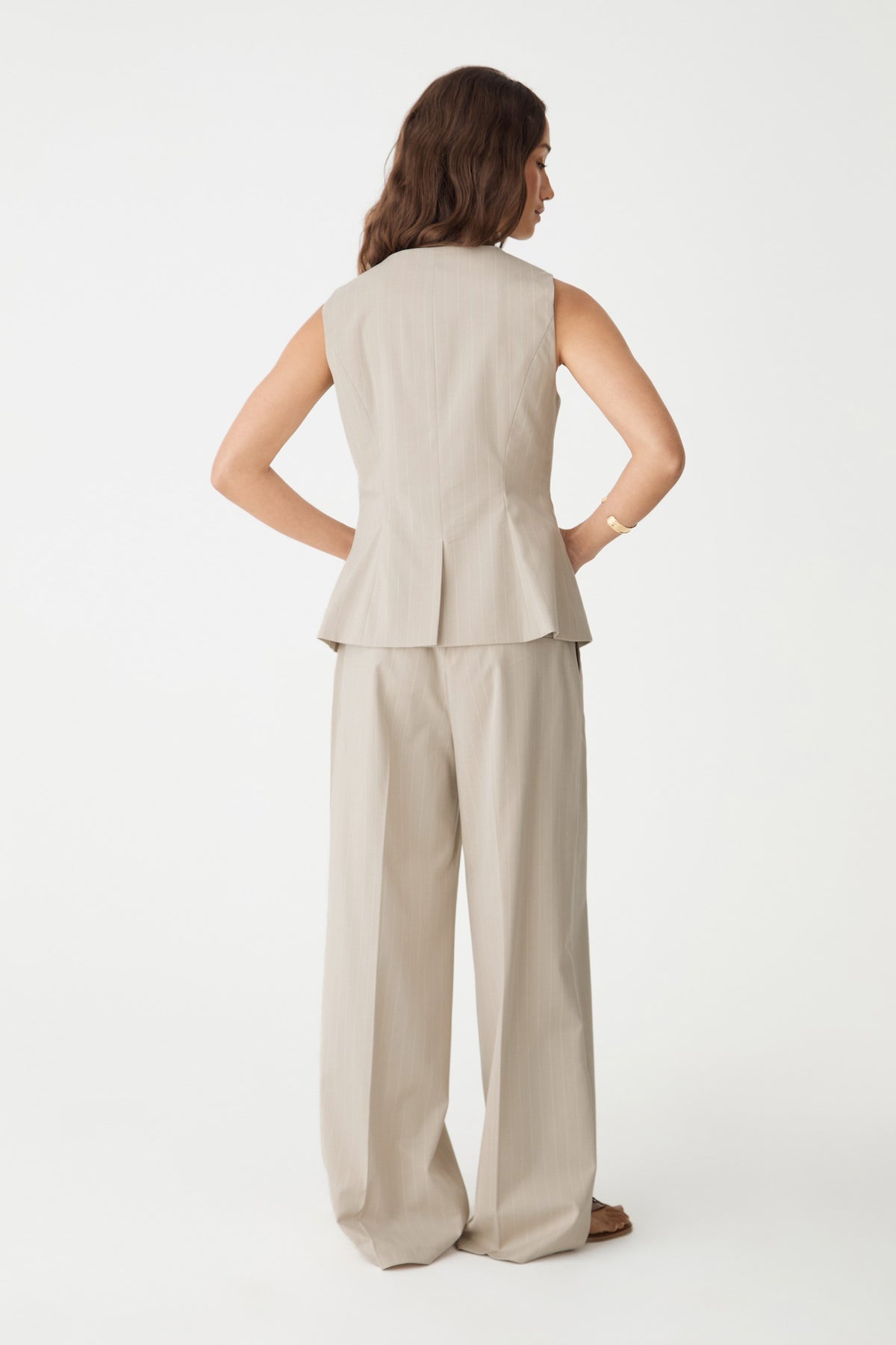 Back view of the beige pinstripe wide leg pants showing waist darts and full-length hem