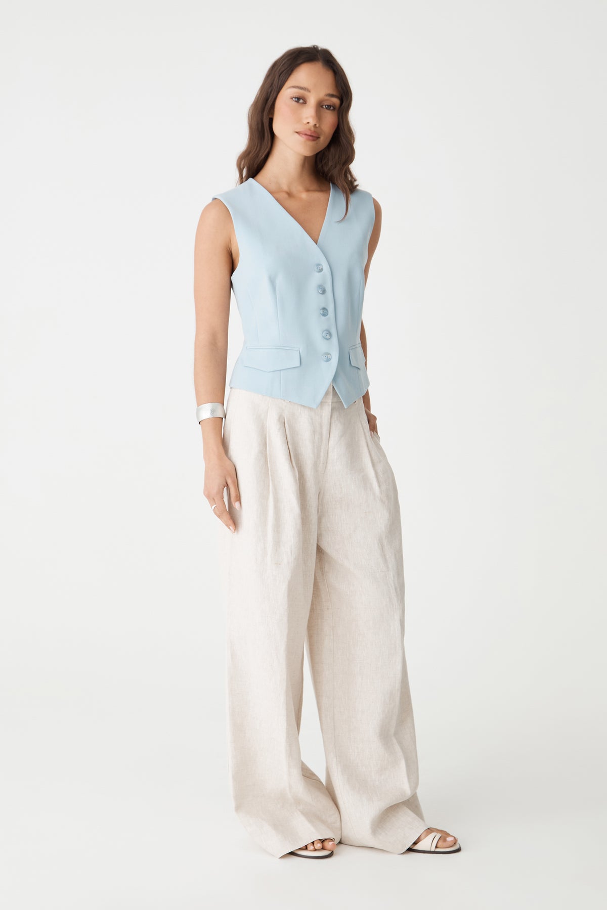 Front view of the sky blue tailored vest showing pointed hem and flap pockets