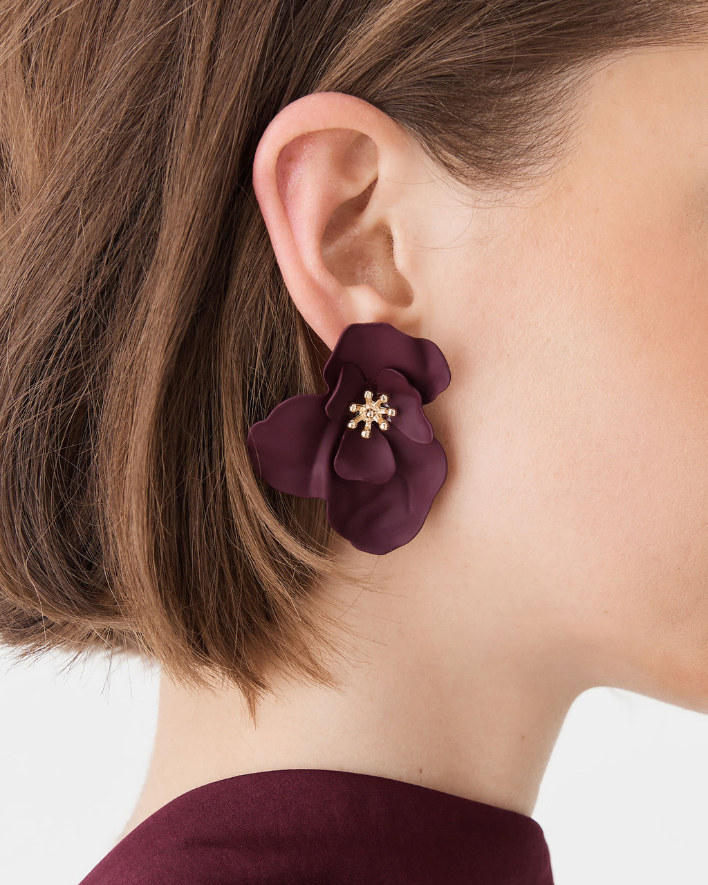 Close-up of curved burgundy petals and beaded gold-tone centre on the ear